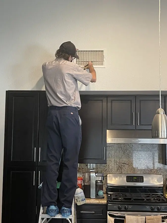 Technician inspecting an air vent during HVAC service in Lynbrook